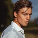 Portrait of a young man outdoors with sunlight creating strong shadows on his face.